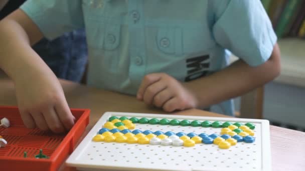 Menino pré-escolar coleta figura usando chips coloridos — Vídeo de Stock