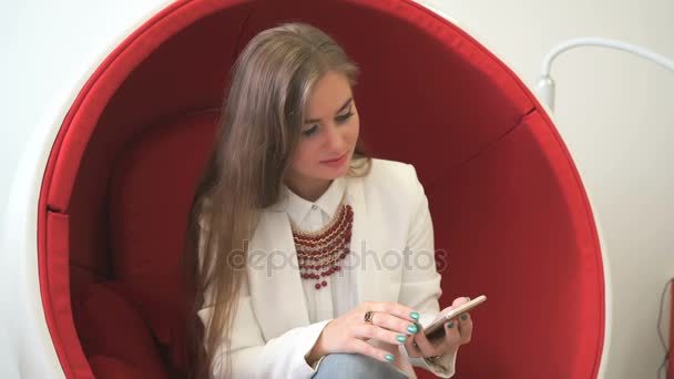 Vrouw client zitten in rode stoel met smartphone — Stockvideo