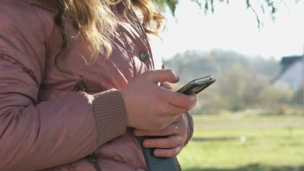 Adolescente menina olha fotos usando um telefone celular — Vídeo de Stock