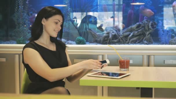 Menina sentada em um café e bebendo um suco — Vídeo de Stock