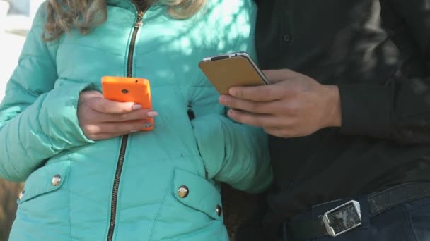 Mladý pár stát a držet mobilní telefony — Stock video