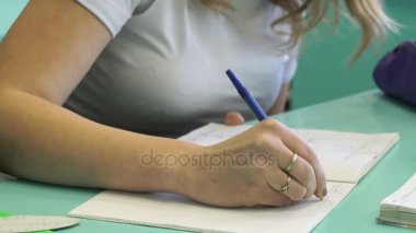 Kız öğrenci ders içinde defterini yazıyor