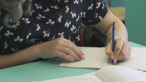 Школьница пишет в своем блокноте на уроке — стоковое видео
