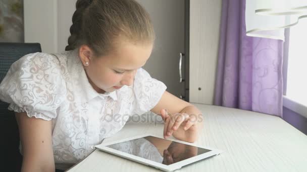Adolescente menina usa um tablet digital na mesa — Vídeo de Stock