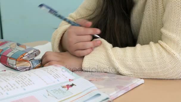 La colegiala escribe en el cuaderno de la clase — Vídeos de Stock