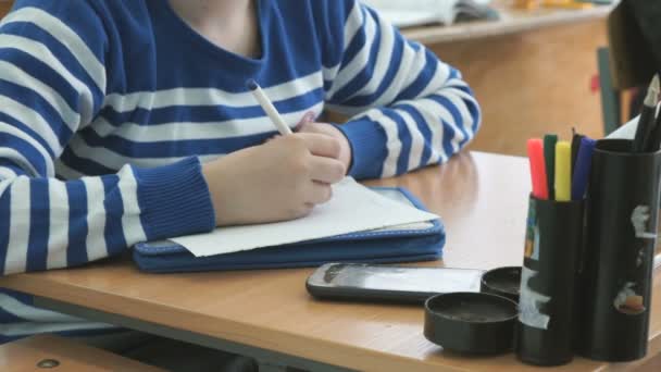 Schoolgirl writes the text on the sheet of paper — Stock Video