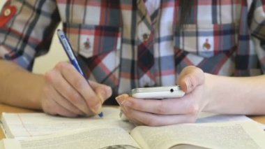 Bir masada oturan genç bir akıllı telefon tutar