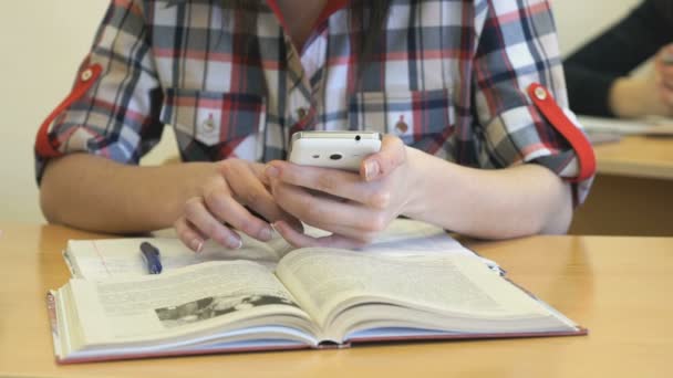 Школьница, сидящая за партой, пишет текст в тетради — стоковое видео