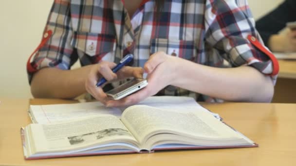 Estudiante sentado en el escritorio escribe texto en copybook — Vídeo de stock