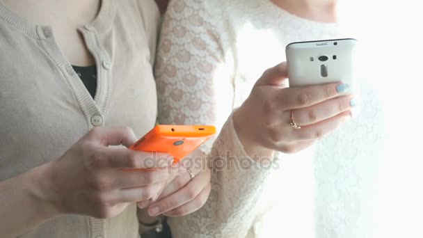 Zwei Mädchen, die sich die Fotos mit Mobiltelefonen ansehen — Stockvideo