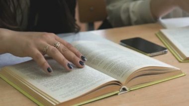 Masada oturan öğrenci kitabın sayfalarını çevirir