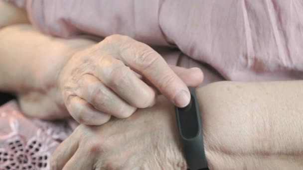 Пожилая женщина касается браслета импульсного монитора — стоковое видео