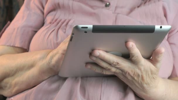 Пожилая женщина 80 лет держит серебряный планшетный компьютер — стоковое видео