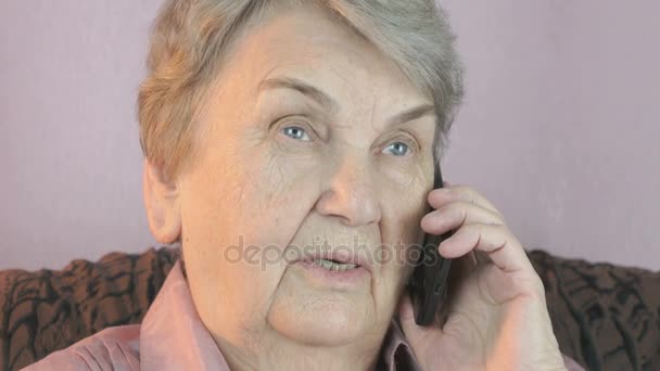 Пожилая женщина 80-х с улыбкой говорит по мобильному телефону — стоковое видео