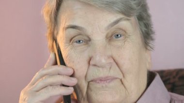 Smartphone üzerinde görüşmeler gülümseyen büyükanne. Yakın çekim