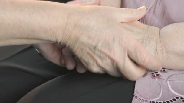 Жінка гладить старі жіночі руки під час хвороби — стокове відео