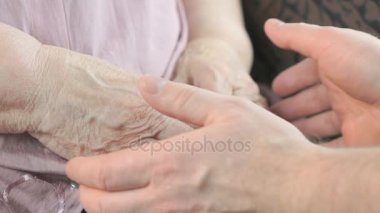 Adam yaşlı buruşuk kadının elleri sıvazlar. Yakın çekim