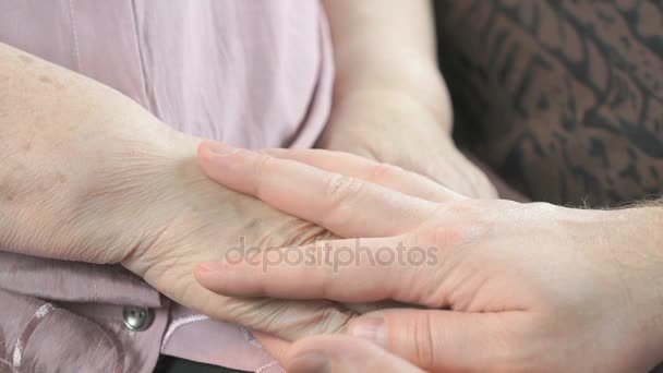 Чоловік тримає старі зморщені руки літньої жінки — стокове відео