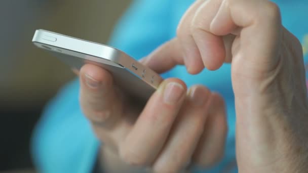 Mujer entra texto en el teléfono móvil de plata en el interior — Vídeo de stock