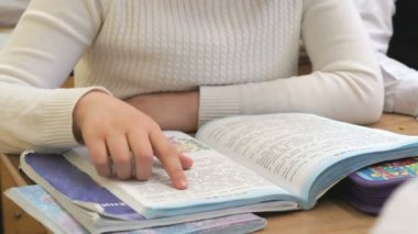 Okul masa başında oturan kız kitap okur