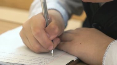 Okul çocuğu metin not defterinde kapalı yazıyor.