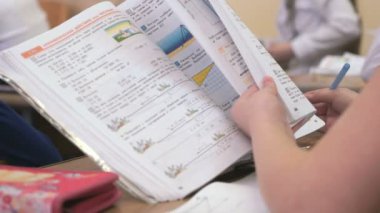 Masada oturan kız öğrenci kitabın sayfalarını çevirir