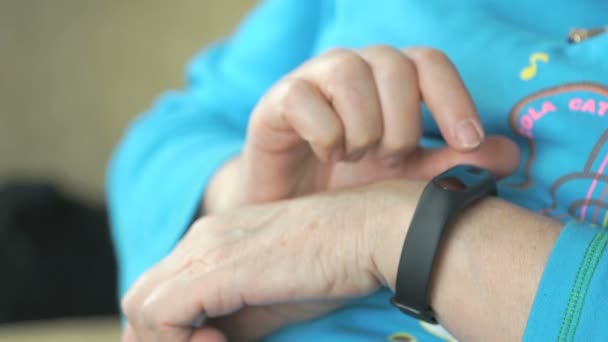 Woman looks at the wristband fitness tracker — Stock Video