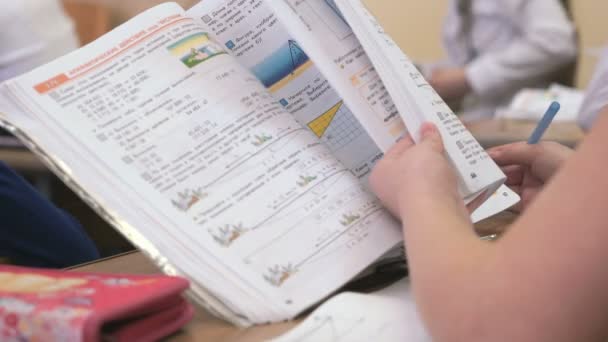 Školačka, sedící u stolu otočí stránky knihy — Stock video