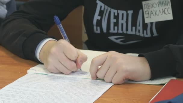 Tonåringen skriver texten i ett häfte på en lektion — Stockvideo