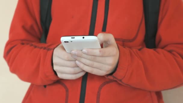 O estudante segurando um smartphone branco dentro de casa — Vídeo de Stock