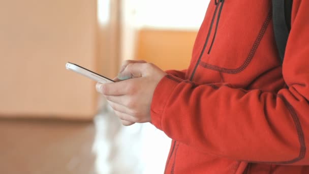Студент тримає білий смартфон у приміщенні — стокове відео