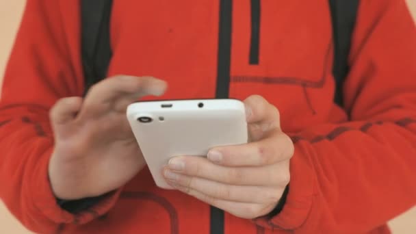 El colegial sosteniendo un celular blanco en el interior — Vídeos de Stock