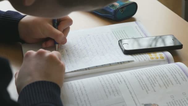 Student schrijft de tekst op een wit vel papier — Stockvideo