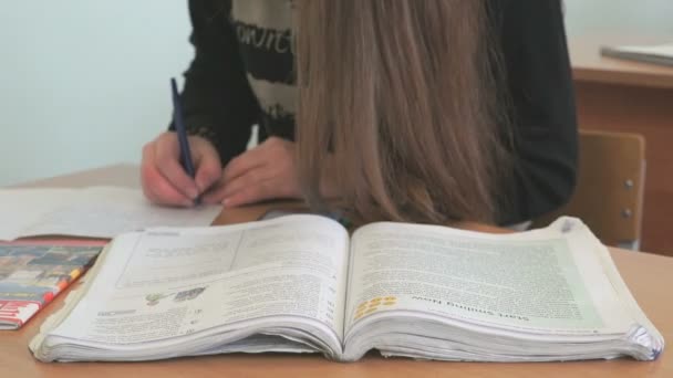 Uczeń zapisuje tekst na białą kartkę papieru — Wideo stockowe