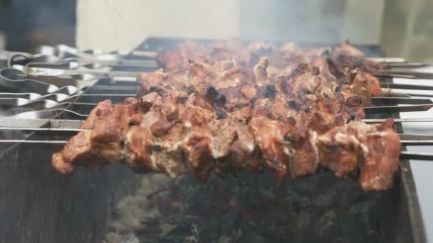 Мясо готовится на металлических шампурах на углях — стоковое видео