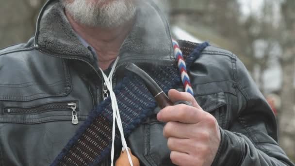 Взрослый мужчина держит в руках деревянную трубку — стоковое видео
