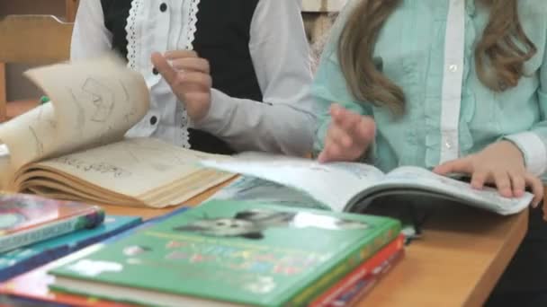 Les enfants assis au bureau retournent les pages du livre — Video