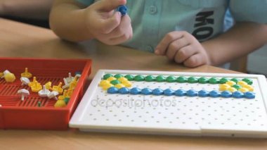 Okul öncesi çocuk renkli fiş kullanarak şekil toplar