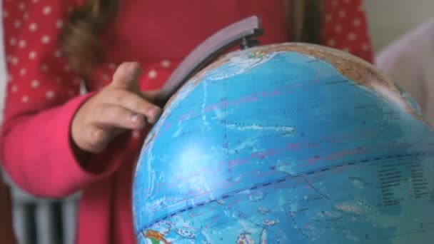 Little girl rotates the globe of world. Close-up — Stock Video