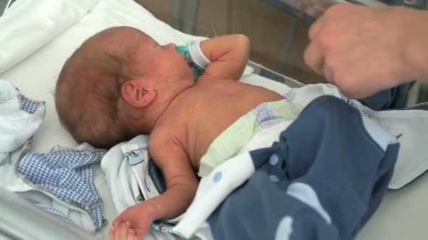 Medical nurse swaddles newborn baby on baby cot — Stock Video