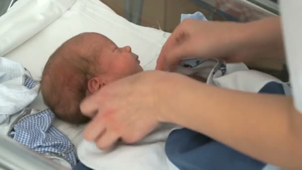 Krankenschwester wickelt Neugeborenes auf Babybett — Stockvideo