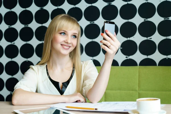 Bir cep telefonu kafede oturan kız tutar