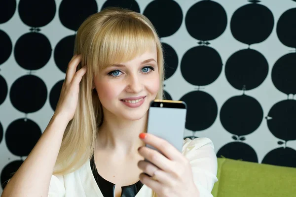 Kafede oturan kız bir akıllı telefon tutar