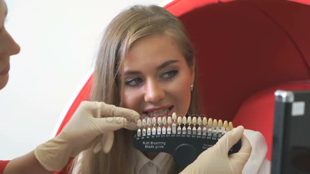Приваблива дівчина дивиться на різноманітність тонів зубів — стокове відео