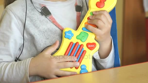 Ребенок играет на игрушечной гитаре в детском саду — стоковое видео