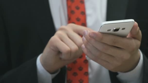 Чоловік тримає білий мобільний телефон в приміщенні — стокове відео