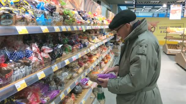 Пожилой человек выбирает хлеб в супермаркете Лента — стоковое видео