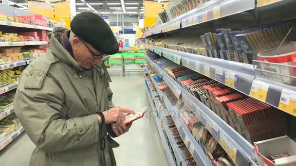 Un homme âgé choisit le chocolat au supermarché Lenta — Video