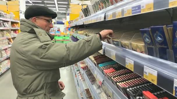 Ηλικιωμένος άνδρας επιλέγει σοκολάτα στο σούπερ μάρκετ ΛΕΝΤΑ — Αρχείο Βίντεο