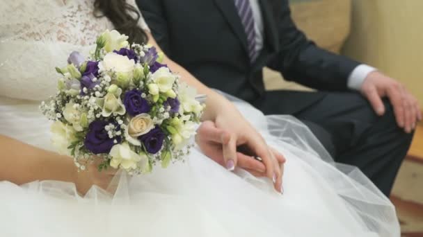 Bride and groom sitting on couch hold hands — Stock Video